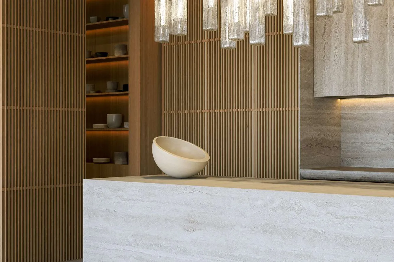 Travertine kitchen island beneath glass pendant lights and slatted timber walls